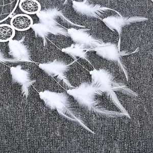 White dreamcatcher wall hanging with delicate feathers and woven loops for boho room decor.