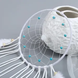 White velvet dream catcher detail shot with blue beads and feathers for indoor home decor.