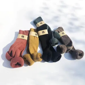 Nahaufnahme von dicken Wintersocken über dem Knie in verschiedenen Farben mit Papierband.