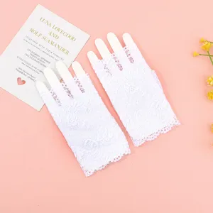 Detalle de guantes de encaje blanco sin dedos elegantes presentados en fondo rosa.