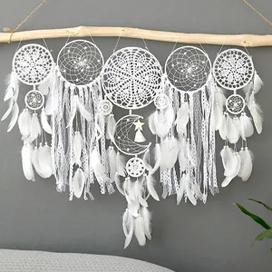 Close-up of handmade white feather dream catcher wall hanging with delicate lace details.