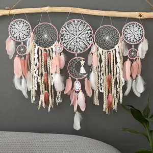 Handmade dream catcher detail showing lace crochet, pink feathers, and rustic hanging branch.