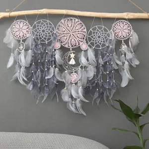 Close-up detail of handmade multi-ring dream catcher with pink lace, feathers, and wall hanging decor.