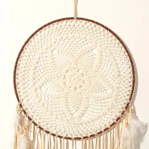 Close-up of the delicate white crocheted lace and natural feathers on a boho dream catcher.