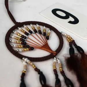 Close-up of handmade brown dream catcher detail, tree of life design with beads and feathers.