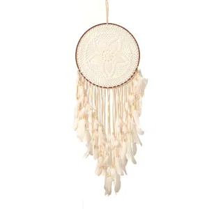 Handmade woven dreamcatcher detail shot featuring soft white feathers and delicate crochet web.