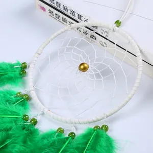 Handmade feather dream catcher detail, white web and green feathers, wall decor hanging.