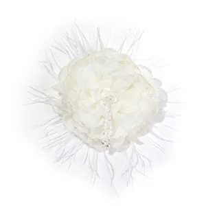 Closeup of white fabric flower brooch with delicate feather trim and hanging crystal bead tassels.