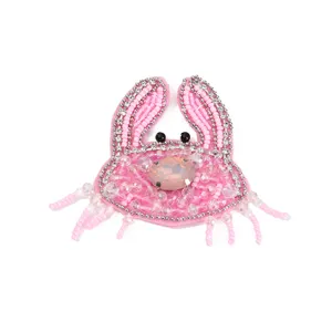Nahaufnahme des handgefertigten rosa Perlenkrabben-Patches mit funkelnden Strasssteinen.