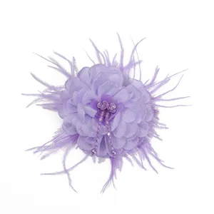 Close-up view of a purple fabric flower with delicate feathers and sparkling rhinestone beads.