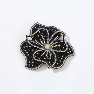 Close up detail of sparkling rhinestone flower patch, black fabric backing DIY craft accessory.