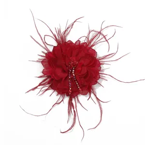 Close up detail of red fabric flower accessory with feather and rhinestone beaded fringe.
