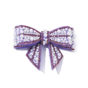 Detailed close-up of a purple rhinestone and pearl bow shoe clip accessory, elegant.
