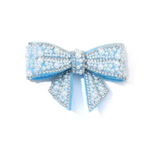 Close-up detail of light blue bow shoe clip with artificial pearls and sparkling rhinestones.