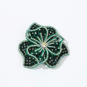 Detailed close-up of green rhinestone flower applique, sparkling crystal fabric patch.