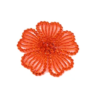 Detailed close-up of vibrant orange rhinestone flower patch, sparkling crystal applique.