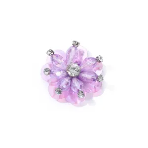 Lila Strass Pailletten Blume Detailaufnahme, glitzerndes Kristallperlen Kleidungszubehör nah.