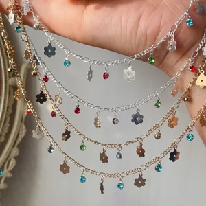 Close-up detail of DIY metallic jewelry chains with colorful rhinestones and flower charms.