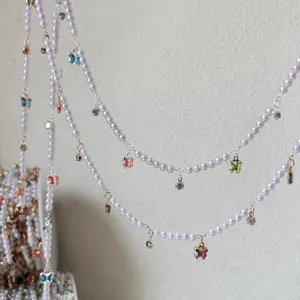 Detail shot of DIY pearl chain with butterfly charms and colorful crystals for handmade crafts.