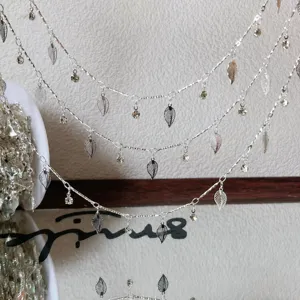 Vista dettagliata della catena con foglie argentate DIY e strass, accessorio nappa.