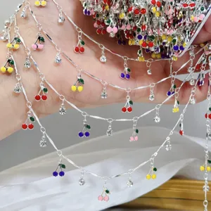 Primo piano e dettaglio della catena pendente con ciliegie smaltate e strass per DIY.