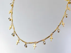 Dettagli in primo piano dell'accessorio gioiello DIY catena croce oro con strass e bastoncini.