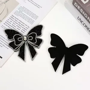 Nahaufnahme von handgemachten Strass-Schleifen und schwarzen Stoff-Aufnähern für Bekleidung.