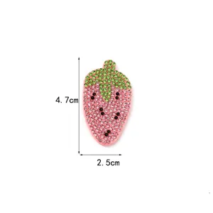Rhinestone strawberry patch detail shot, sparkling pink and green crystals on fabric.