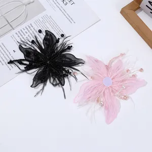 Primer plano de flor de organza y plumas con cuentas, ideal para decorar vestidos.