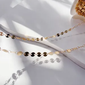 Primo piano di catena con dischi piatti dorati, maglie metalliche lucide per accessori fai da te.