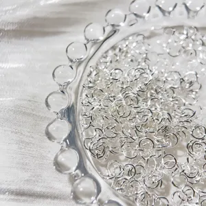Vue detaillee des anneaux de saut en argent dans un plat en verre, ideal pour les bijoux DIY.