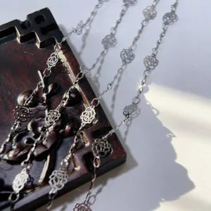 Detailed closeup of metal hollow rose flower chain DIY jewelry accessory, fine link.