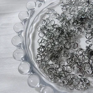 Gros plan détaillé des anneaux de saut en argent dans un bol en verre pour bijoux faits main.