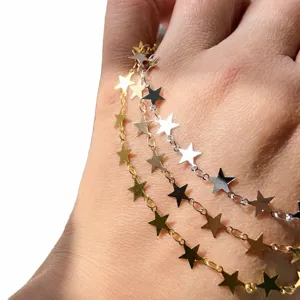 Mano che indossa un accessorio di gioielleria con catena di stelle multi-filo, metallo lucido.