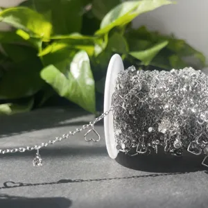Dettaglio catena DIY argentata con zircone e ciondoli a cuore per creazione gioielli fatti a mano