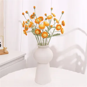 Handmade crochet orange daisy flower bouquet placed in white ceramic vase for home decor