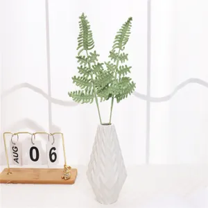 Crochet fern leaf plant decor detail view in white geometric vase for home interior.