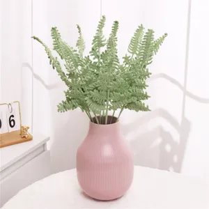 Handmade crochet fern leaves in pink vase, detailed view of knitted plant home decor.