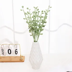 Knitted fern plant artificial flower accessory detail view, green wool floral decor in white vase.