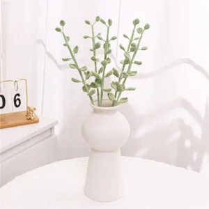 Detailed shot of handmade crochet eucalyptus leaves in a modern white ceramic vase interior decor.