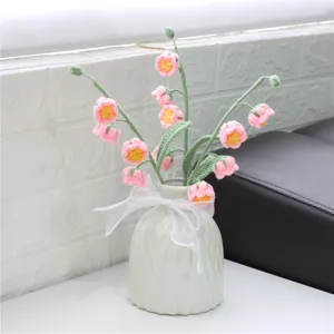 Handmade crochet flower bouquet detail view with pink blossoms and white ceramic vase decor.