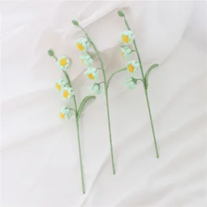 Handmade crochet lily of the valley flower detail view, green yarn botanical craft decor.