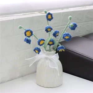 Handmade crochet blue flower bouquet in white ceramic vase, delicate knitted room decor detail.