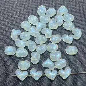 Vista detallada de cuentas de corazón iridiscentes de acrílico para joyería DIY artesanal.