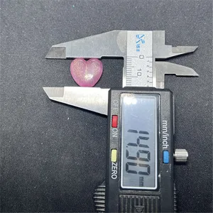 Close-up detail shot of a pink glitter acrylic heart bead being measured with digital caliper.