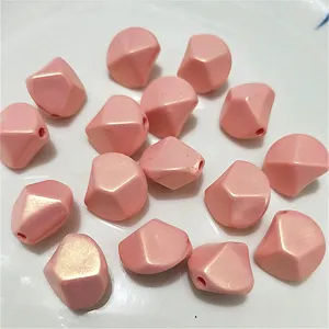 Close-up of pink irregular diamond acrylic loose beads, glossy mermaid finish, DIY craft.