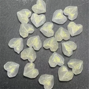 Close-up of translucent faceted heart beads with gold glitter for DIY handmade craft jewelry.