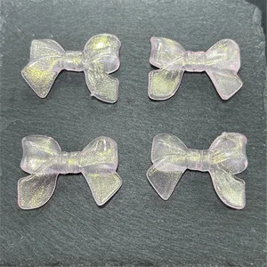Detailed close-up of translucent pink bow beads with gold glitter for DIY crafts and jewelry.