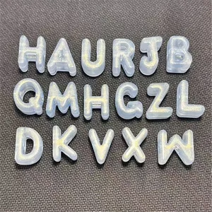 Primer plano de cuentas de letras de acrílico con efecto purpurina para llaveros DIY manualidades.