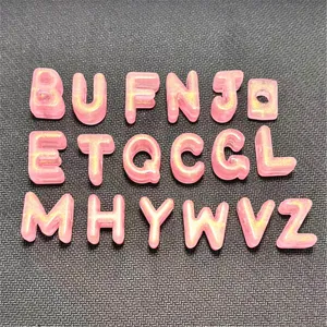 Detalle de cuentas de letras de acrílico brillante rosa, dijes de alfabeto para joyas.